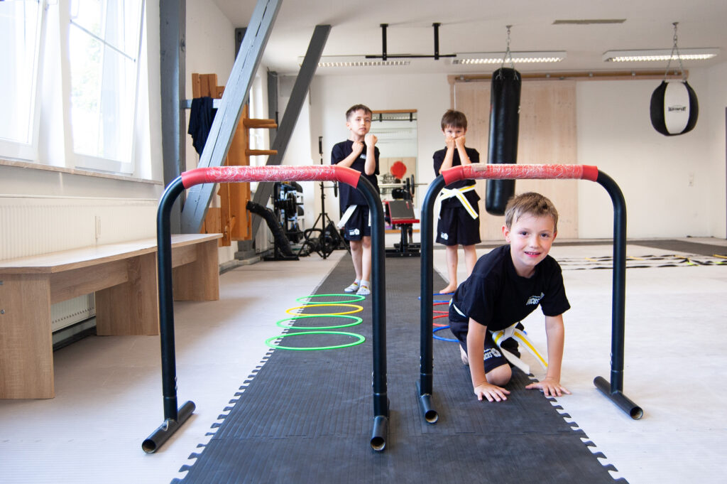 Ein Kind krabbelt während dem Training unter einem Hinderniss hindurch.