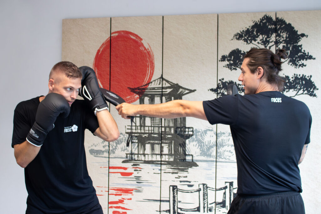 Der Trainer zeigt dem Schüler im Boxtraining wie er seinen Kopf bei einem Angriff schützen kann.