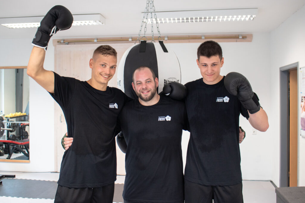 Drei Männer mit Boxhandschuhen die sich umarmen aus dem Kurs Boxen in Wangen im Allgäu.