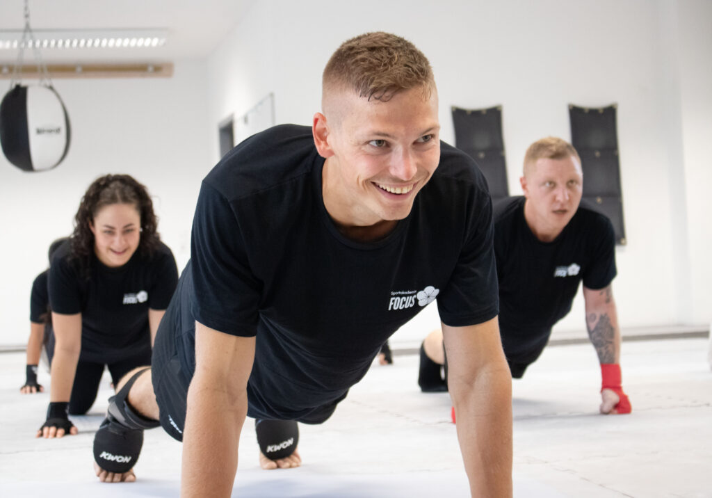 Die Schüler des Kickboxtrainings machen Liegestützen.