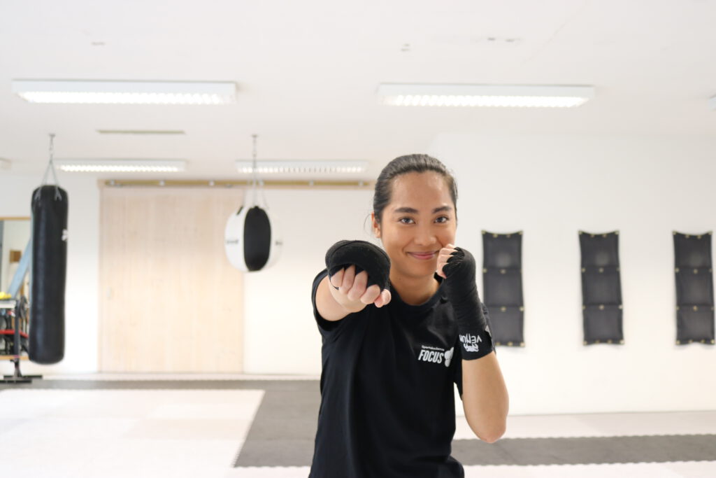 Eine Frau die im Boxtraining mit gerader Faust nach vorne schlägt.