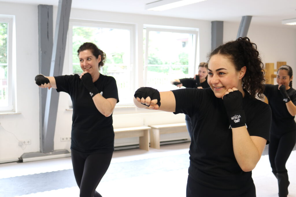 Vier Frauen die gerade dabei sind Boxen zu lernen und einen Haken ausführen.