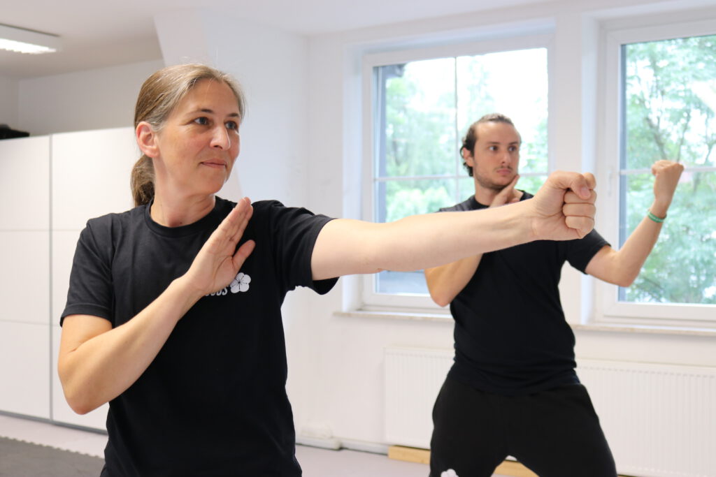 Ein Mann und eine Frau die ihre Faust ballen und ein Technik des Wing Chun lernen.