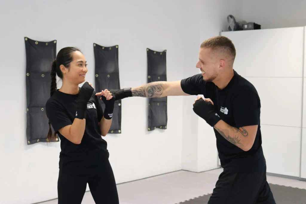 Ein Mann versucht im Kickboxtraining die Schulter einer Frau zu erreichen während die Frau ausweicht.