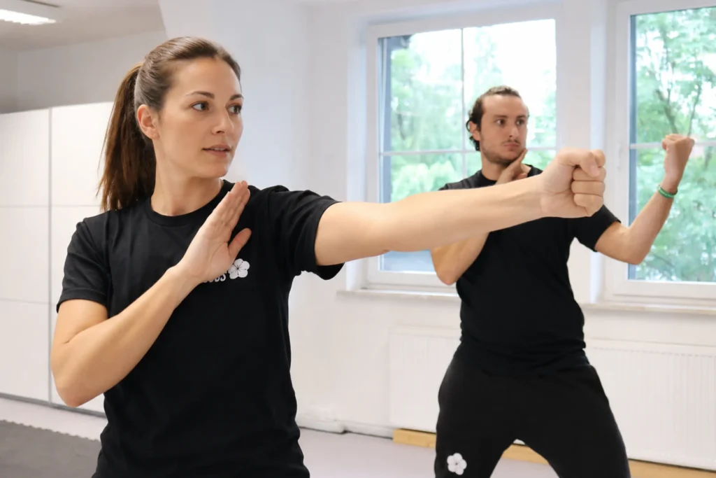 Ein Mann und eine Frau die ihre Faust ballen und ein Technik des Wing Chun lernen.